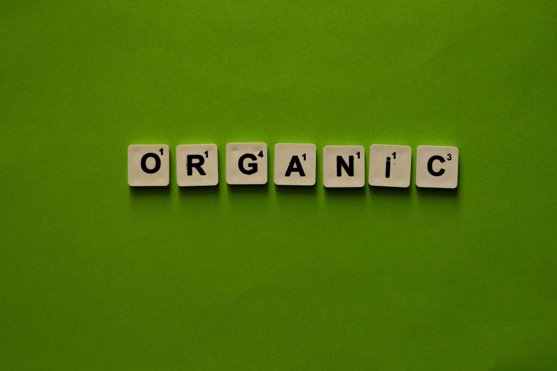 Scrabble tiles spelling 'Organic' on a vibrant green background, emphasizing sustainability.