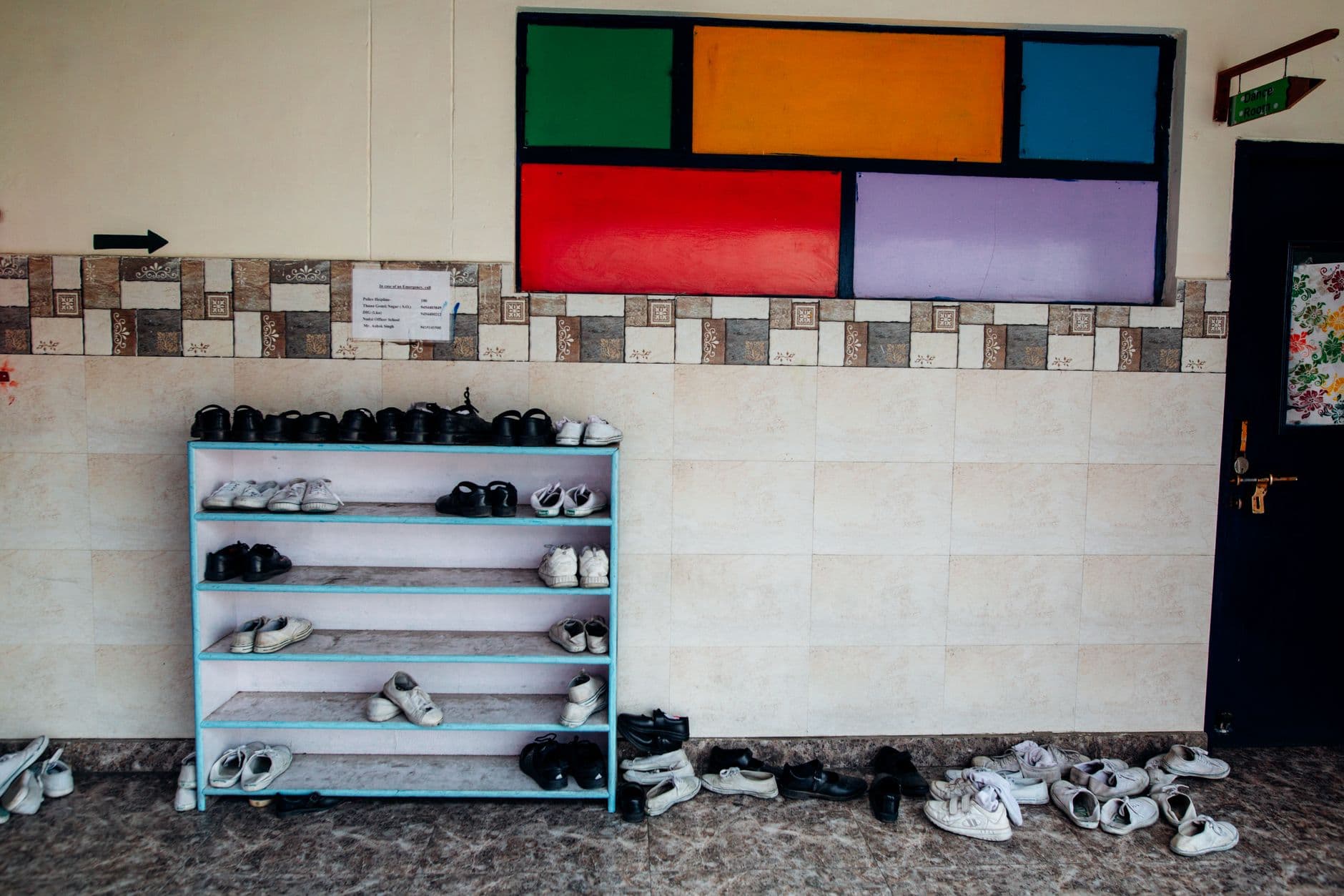 A school hallway with a colorful wall and neat shoe rack arrangement.