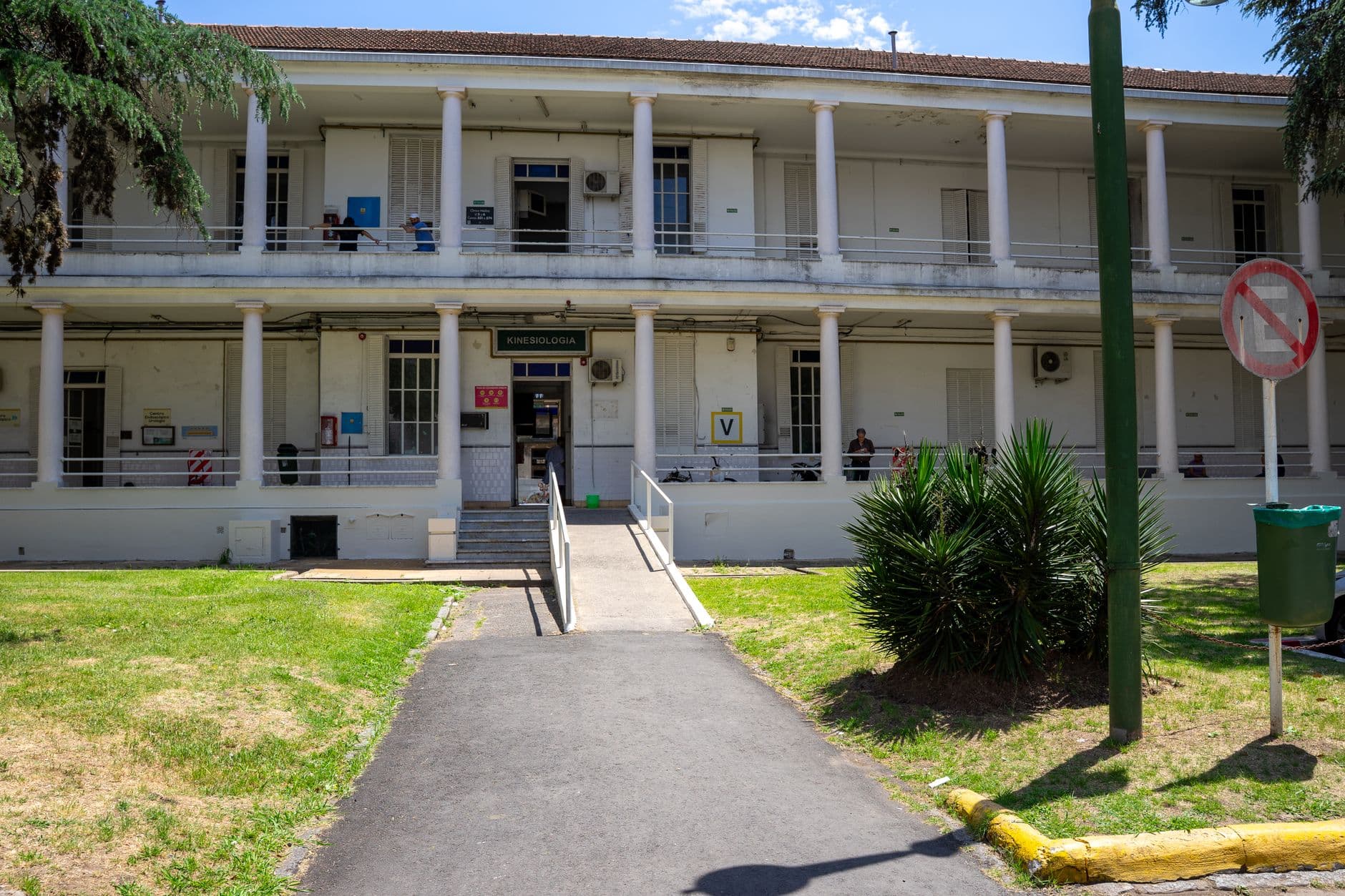 Exterior view of a historic building with columns, surrounded by greenery and a clear sky.