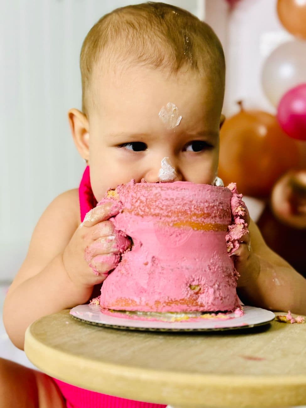 Cute baby with a pink cake during a fun birthday celebration.