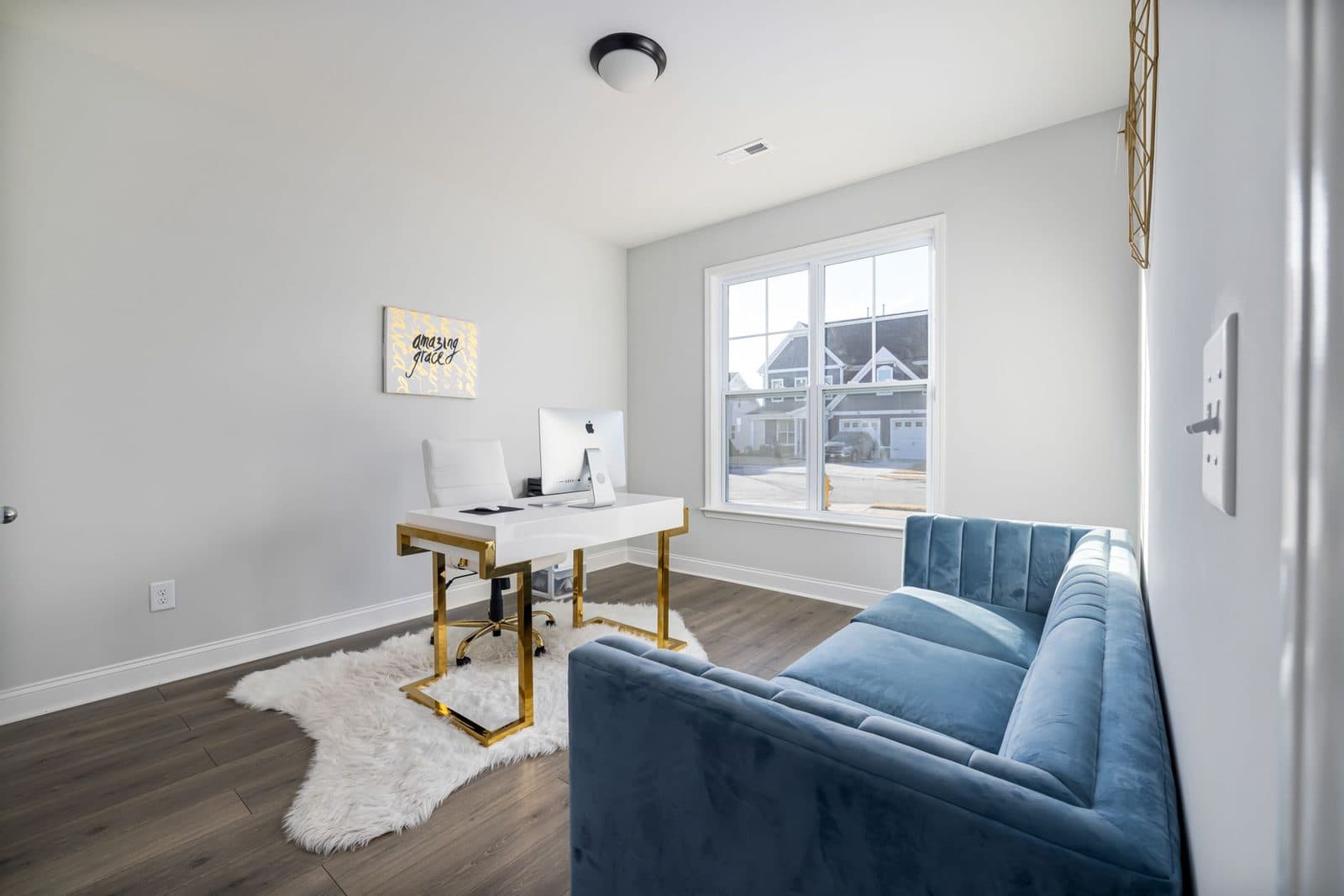 A stylish modern home office featuring a velvet couch and sleek desk with natural light.