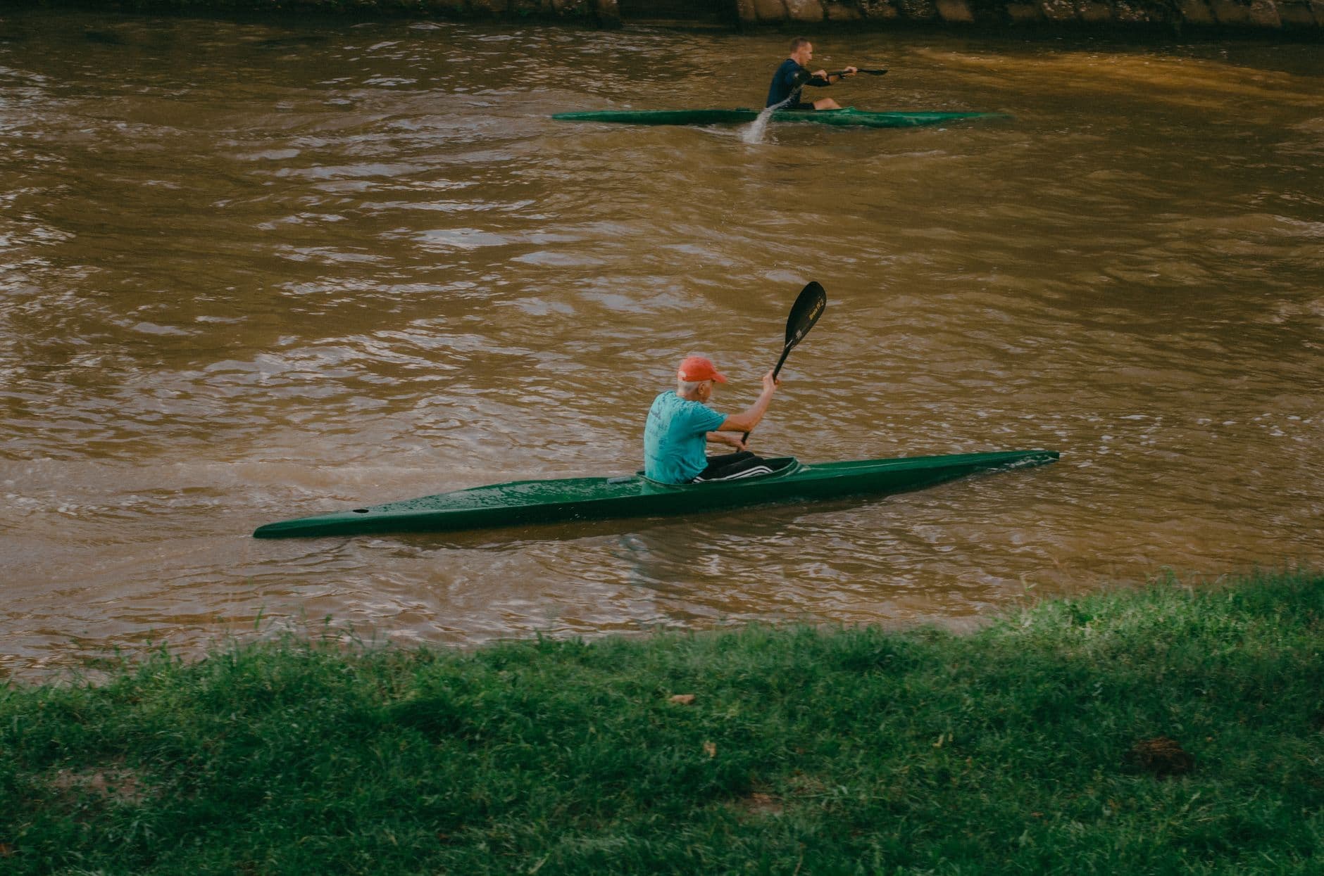 Two adults kayaking on a flowing river, enjoying outdoor leisure activities in summer.