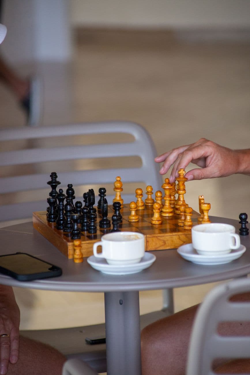 A close-up of a chess game with coffee cups on a table in a relaxed setting.