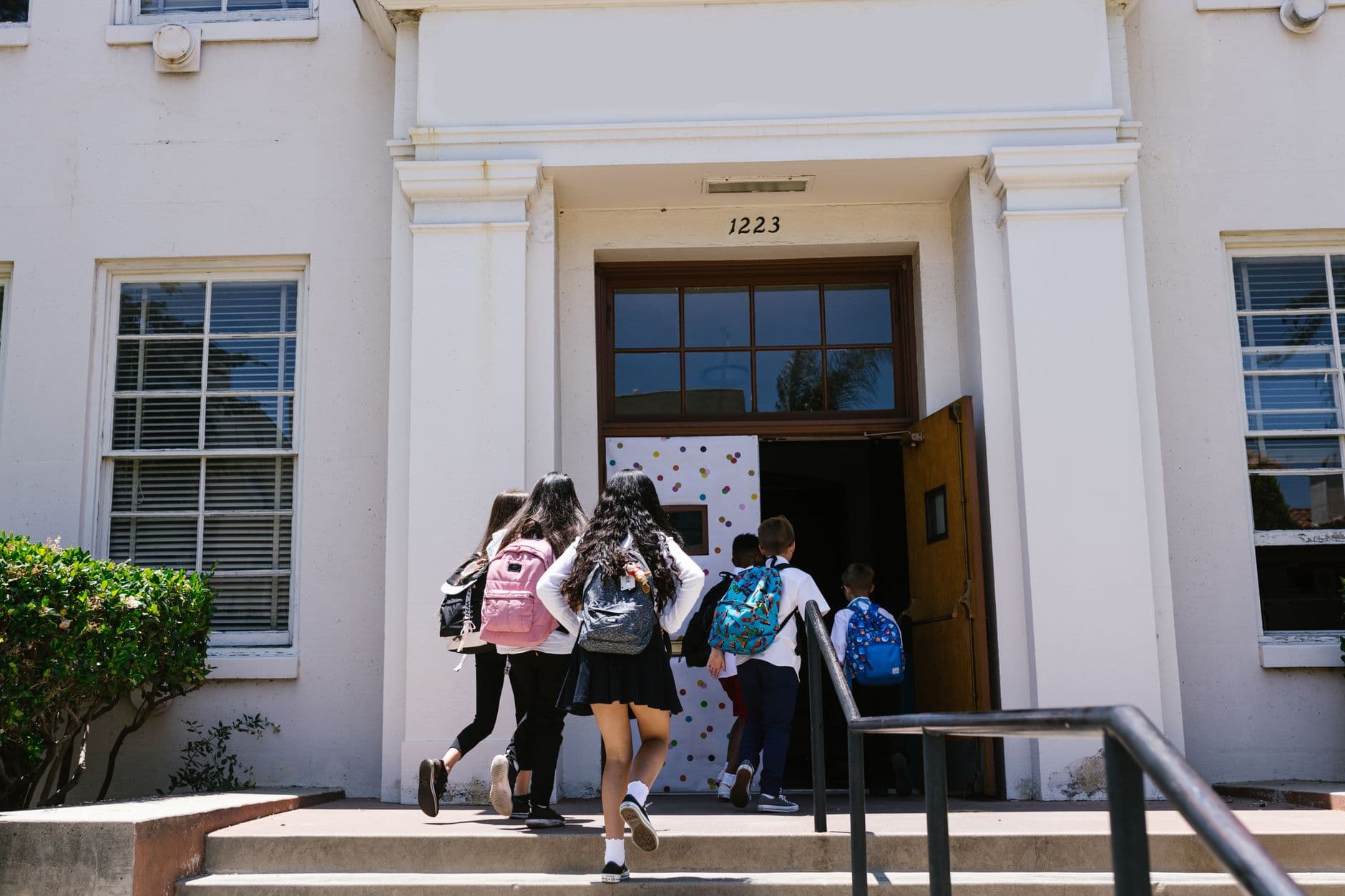 Group of students with backpacks entering a school building. Perfect for back-to-school themes.