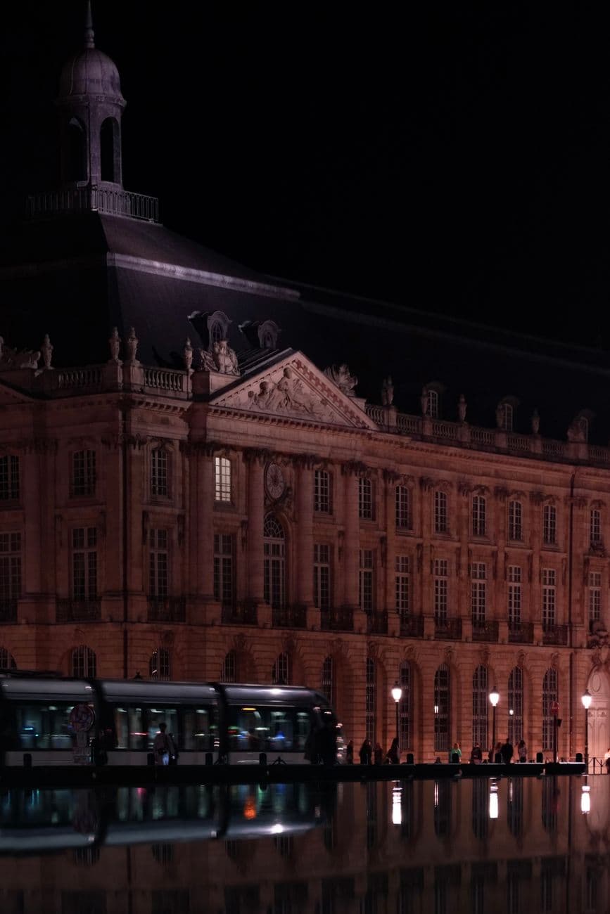 Place de la Bourse in Bordeaux illuminated at night, reflecting on water.