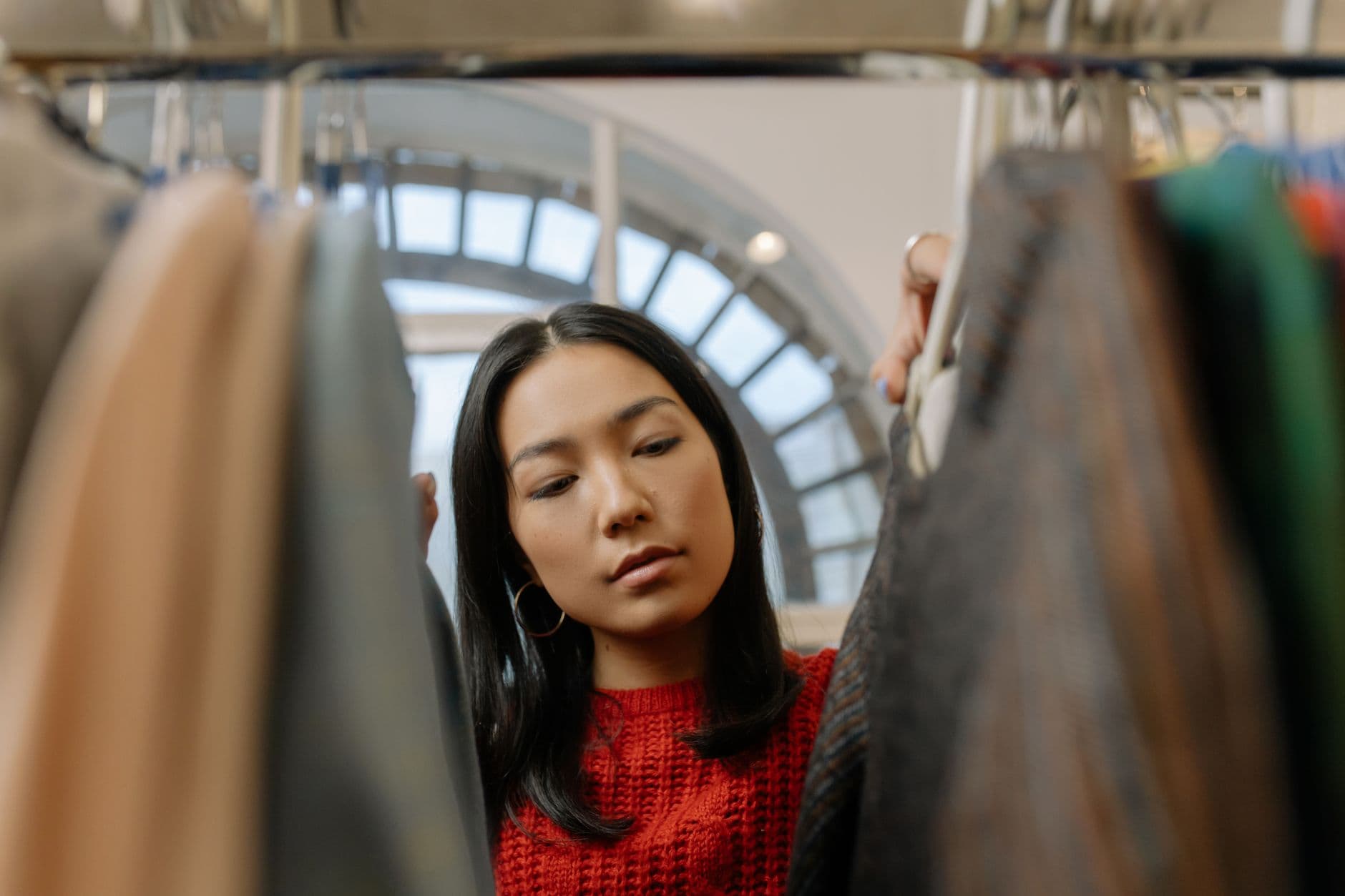 A young woman explores clothing options in a stylish boutique.