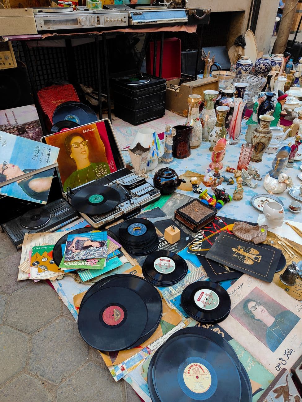 Explore a variety of vintage vinyl records and retro items displayed at an outdoor flea market stall.