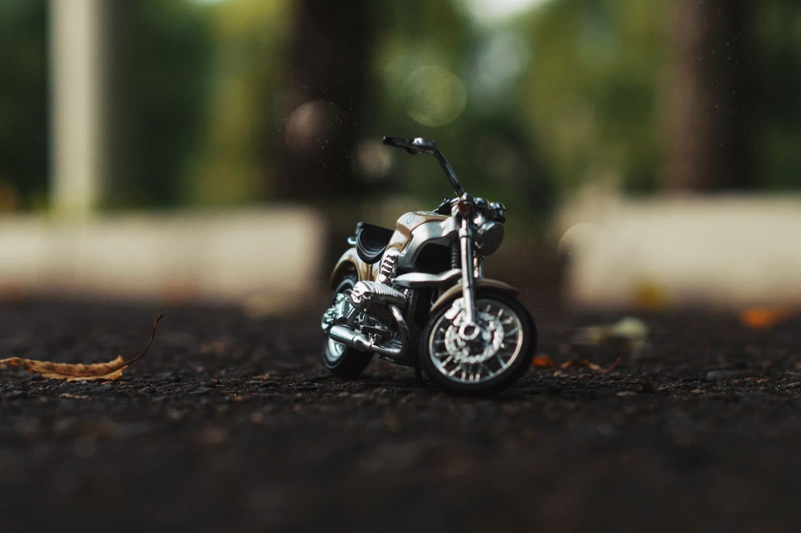 A close-up shot of a miniature motorcycle replica on an outdoor surface with blurred background.