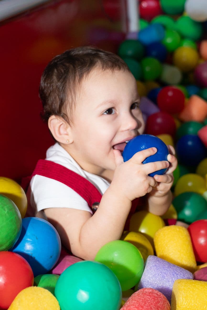 Cute baby joyfully playing with colorful plastic balls in a fun indoor play area.