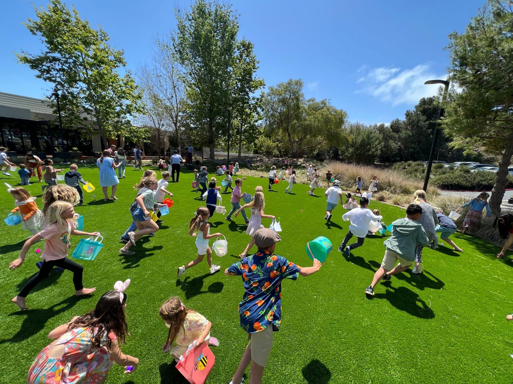 A lively scene of children participating in an Easter egg hunt on a sunny day.
