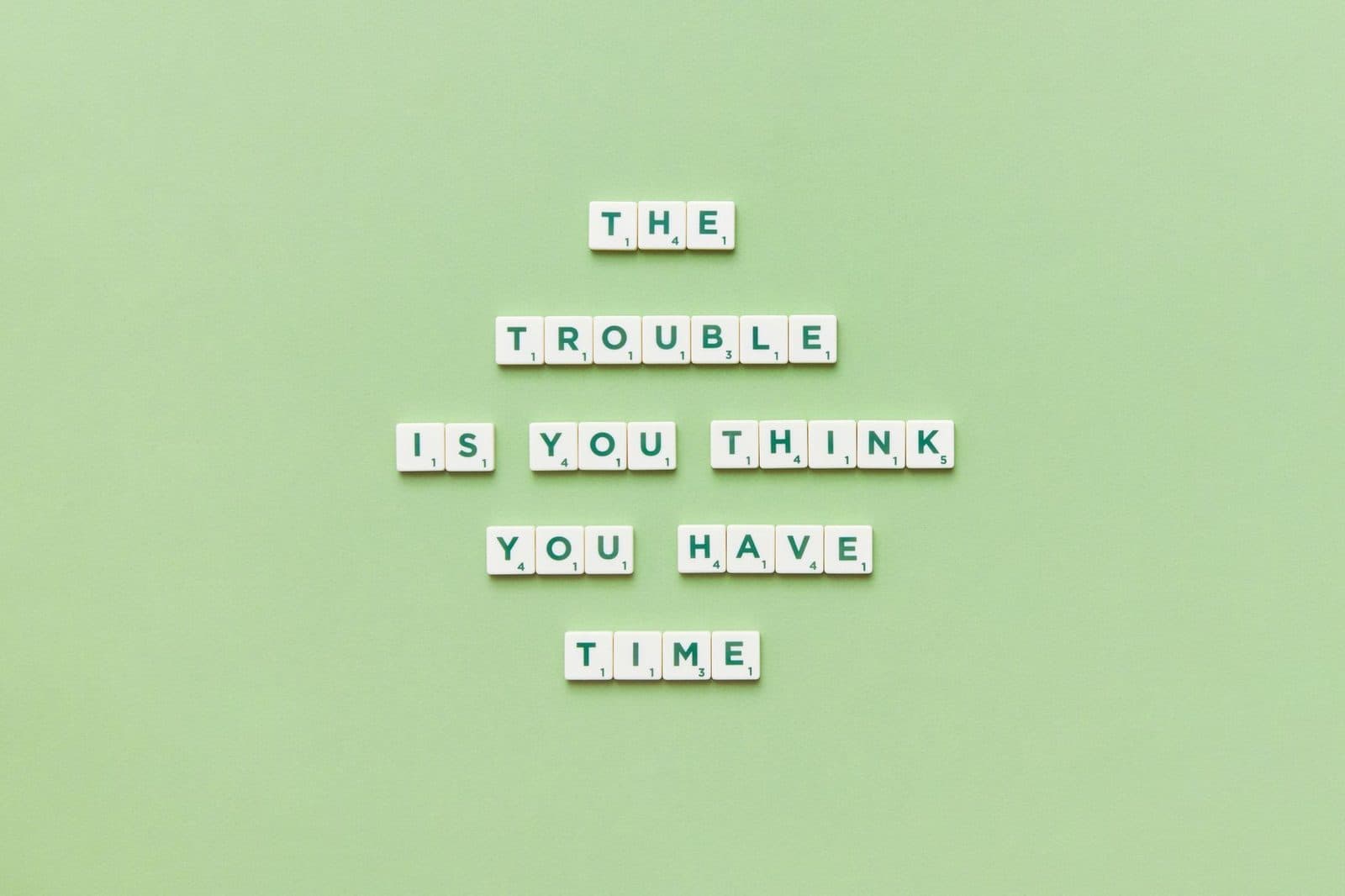 Scrabble tiles arranged to spell a motivational quote against a green background.