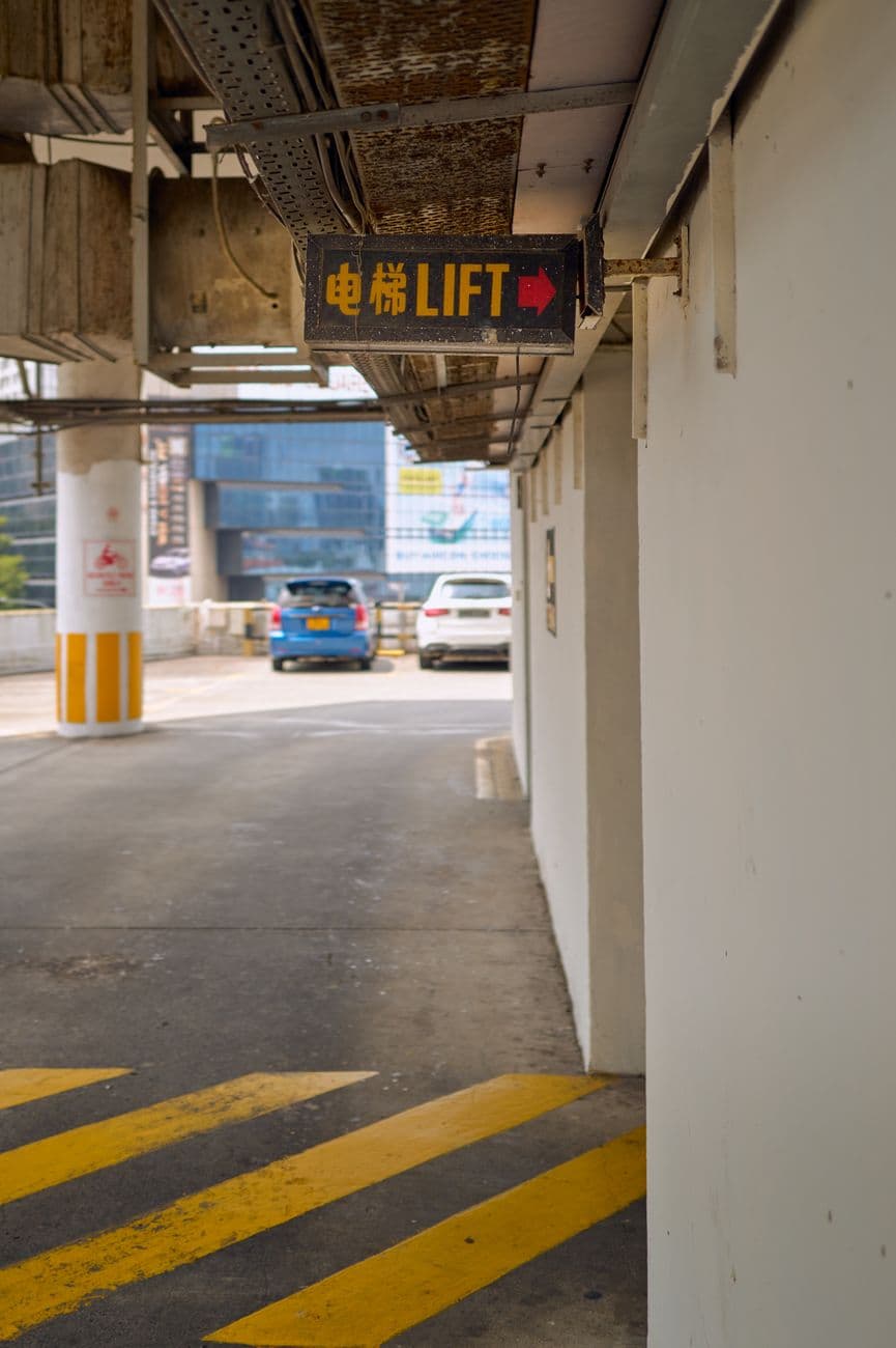 Image of a parking garage with a bilingual lift sign and city backdrop.