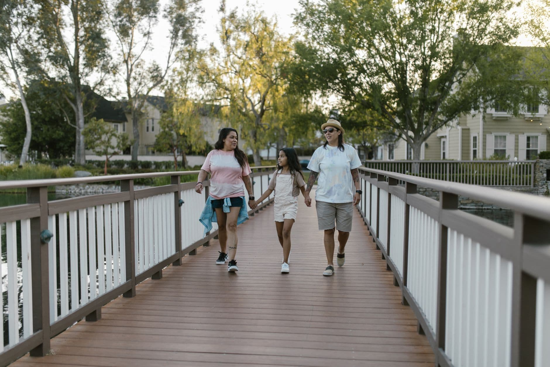 A joyful family enjoying a summer walk on a scenic bridge, holding hands and smiling.