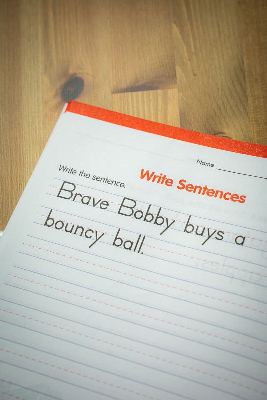 Close-up of an elementary school workbook page for learning sentence structure with visible handwriting.