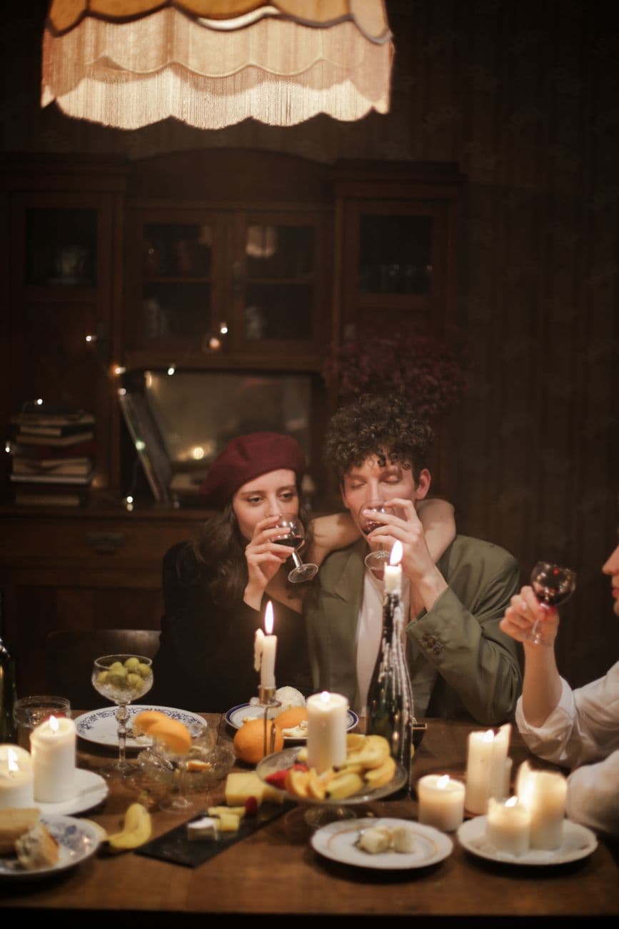 A warm and intimate candlelit dinner with friends, enjoying wine and a cozy atmosphere.
