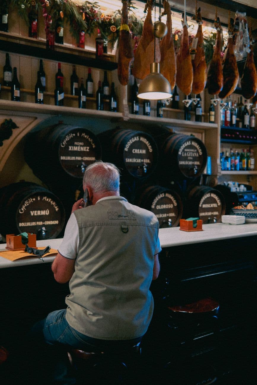 A cozy Seville tapas bar with traditional decor and hanging cured meats.