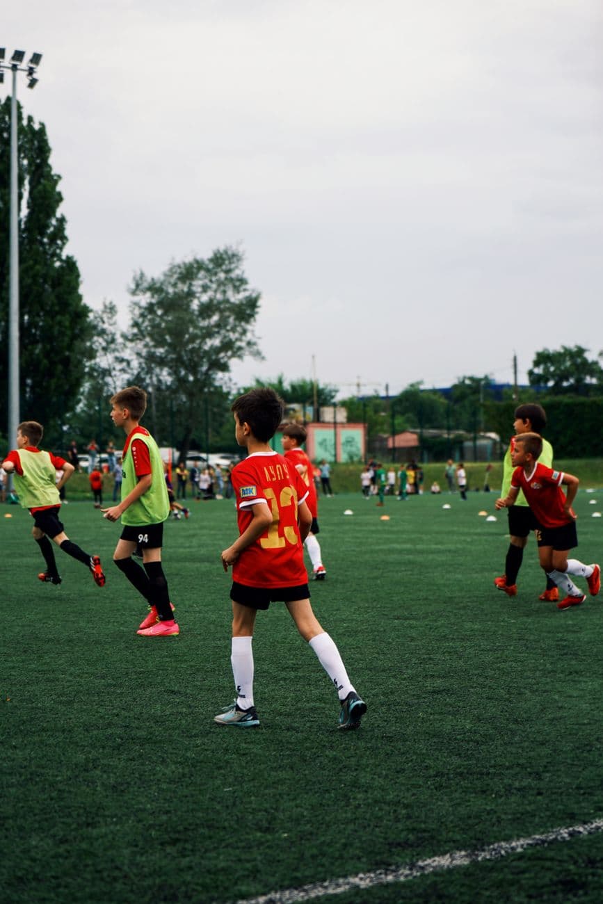 Young kids playing soccer on a green field during the day. Engaged in a fun sporting activity.