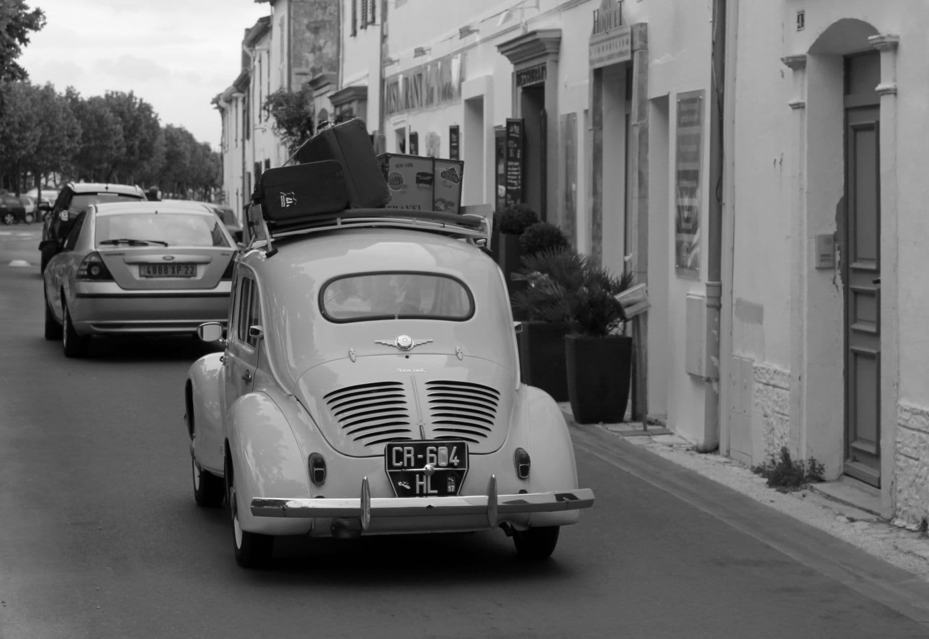 Black and white photo of a vintage car on a city street, evoking nostalgia.