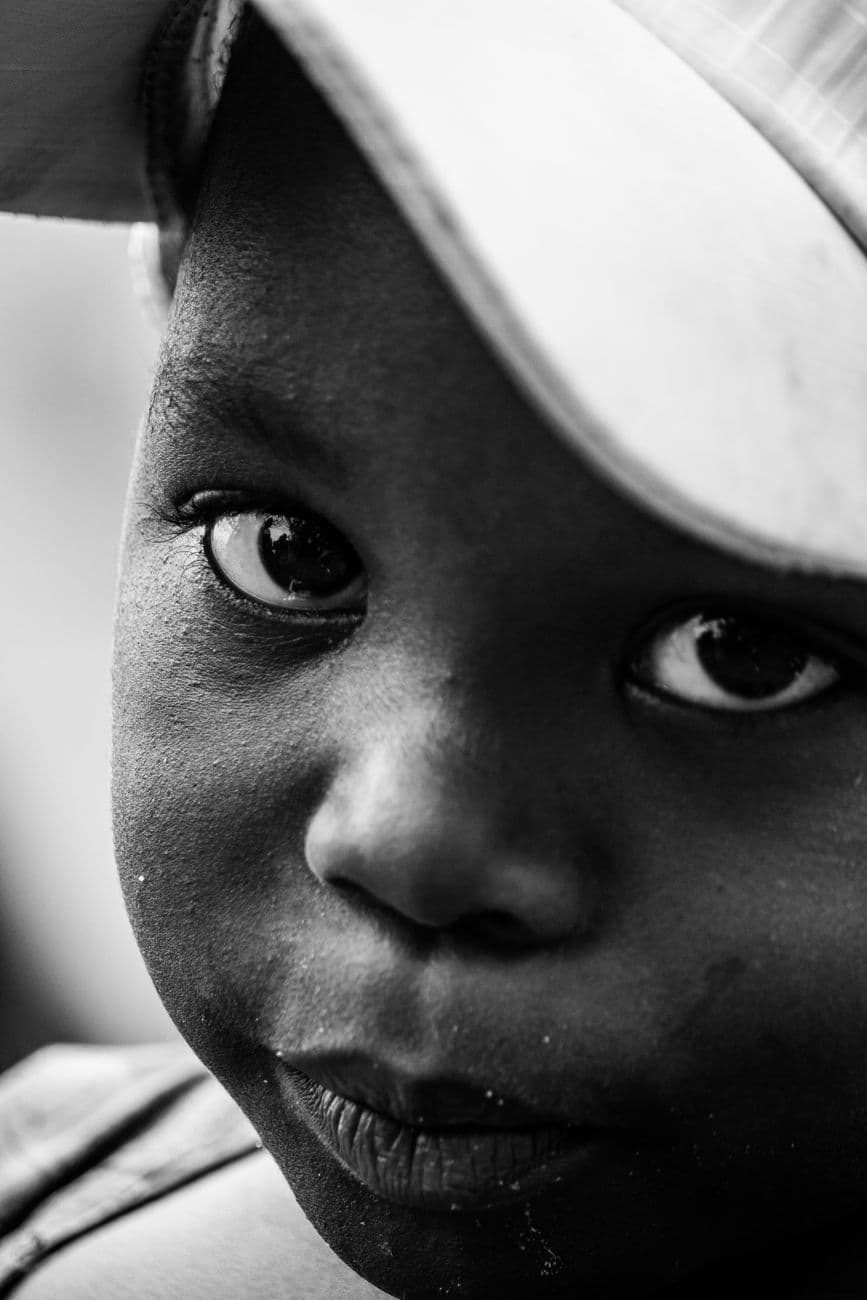 Close-up black and white portrait of a young boy in Bujumbura displaying innocence and curiosity.