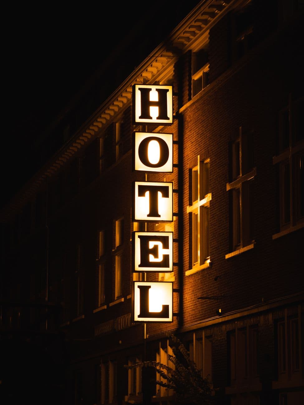 A bright hotel sign glowing on a building facade during nighttime.