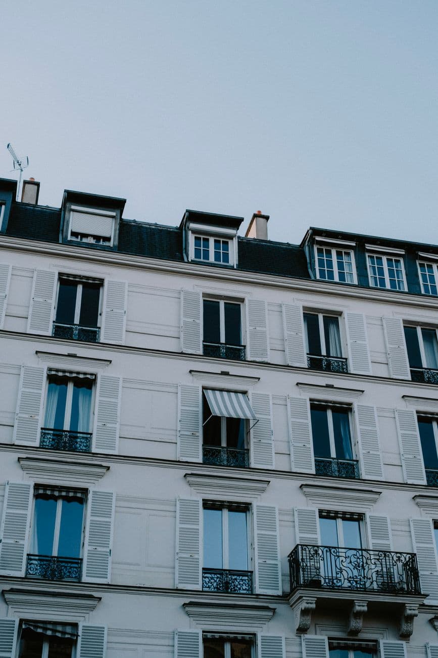 Close-up view of a classic Parisian building facade with white shutters and elegant balconies.