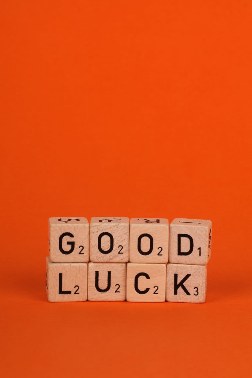 Wooden tiles forming 'Good Luck' on a bold orange backdrop, conveying a message of encouragement.