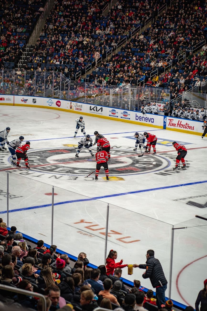 Intense hockey face-off amidst cheering crowd in Québec's vibrant stadium, showcasing sports energy.