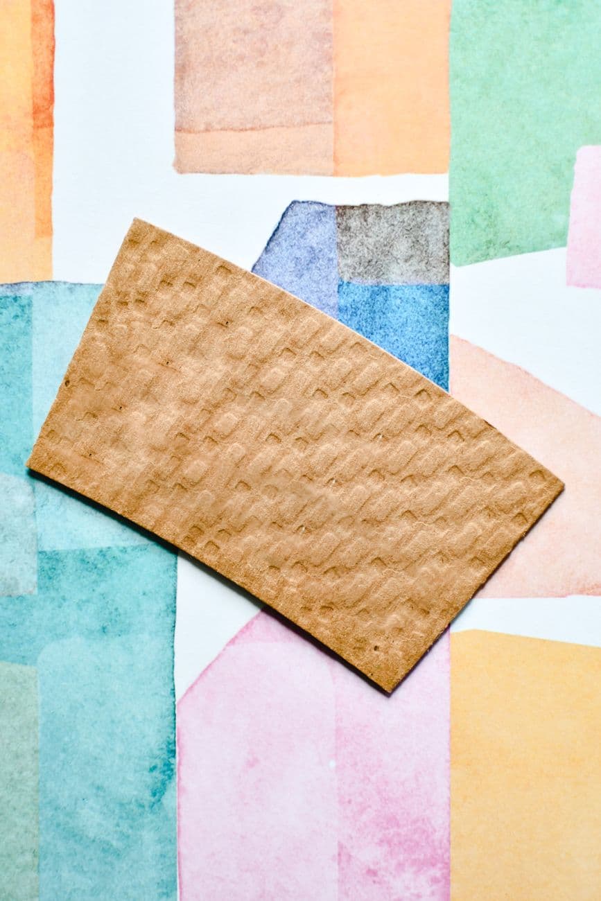 Vibrant abstract background featuring textured cardboard on colorful watercolor blocks.