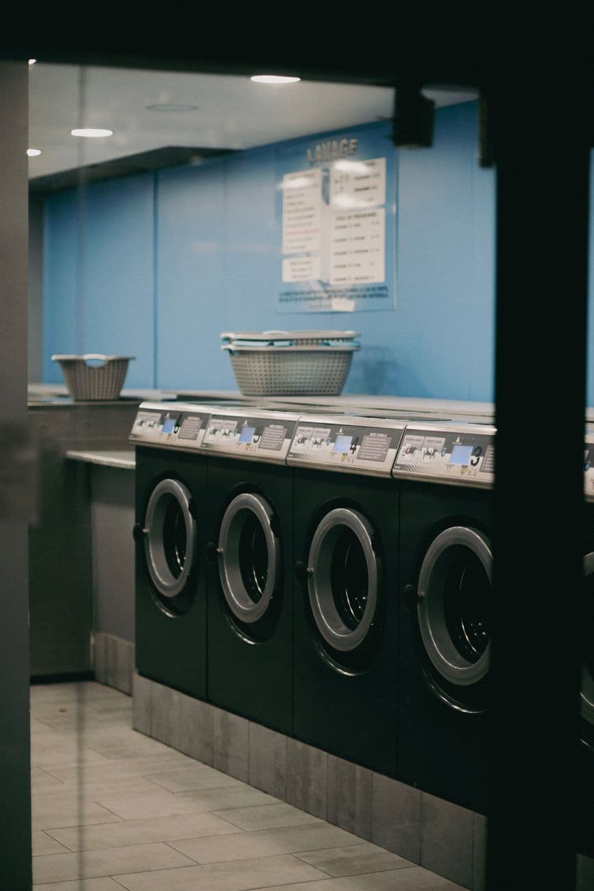 Interior view of a modern laundromat with multiple washing machines lined up.