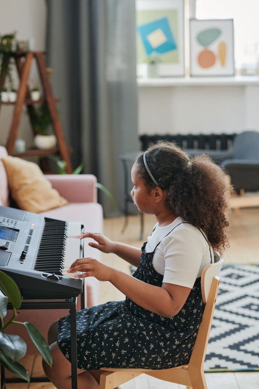 A child playing a keyboard indoors, creating music in a cozy and artistic living room setting.