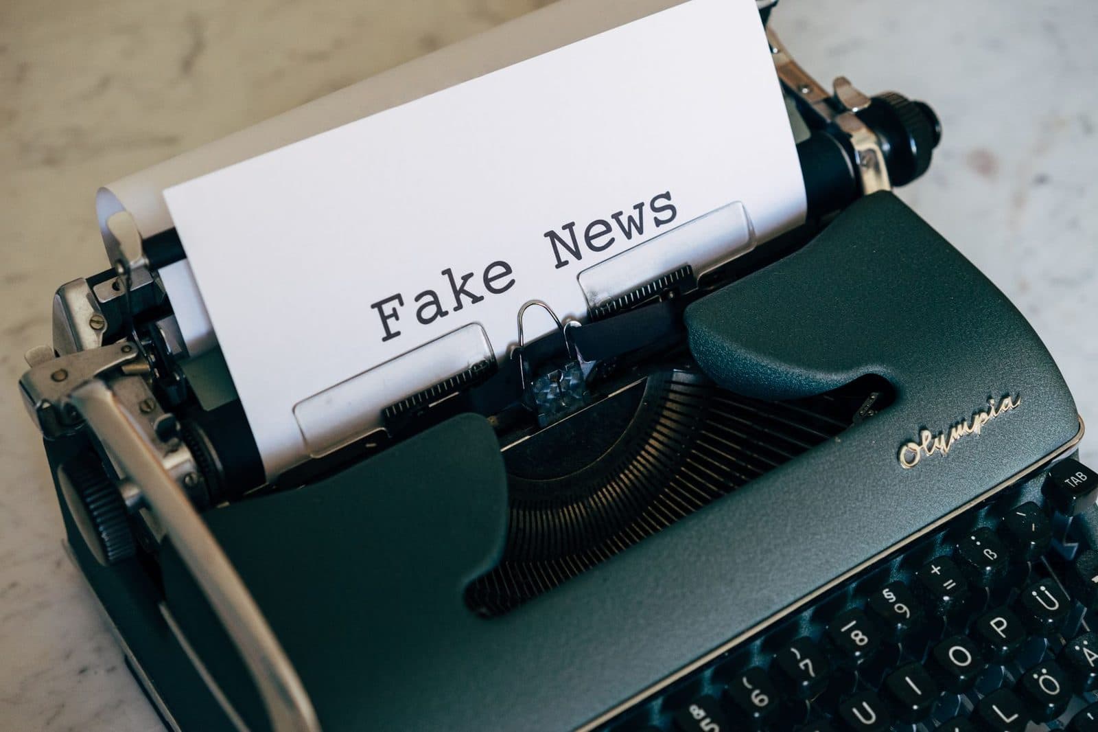 Close-up of a vintage typewriter displaying the words 'Fake News' on paper.