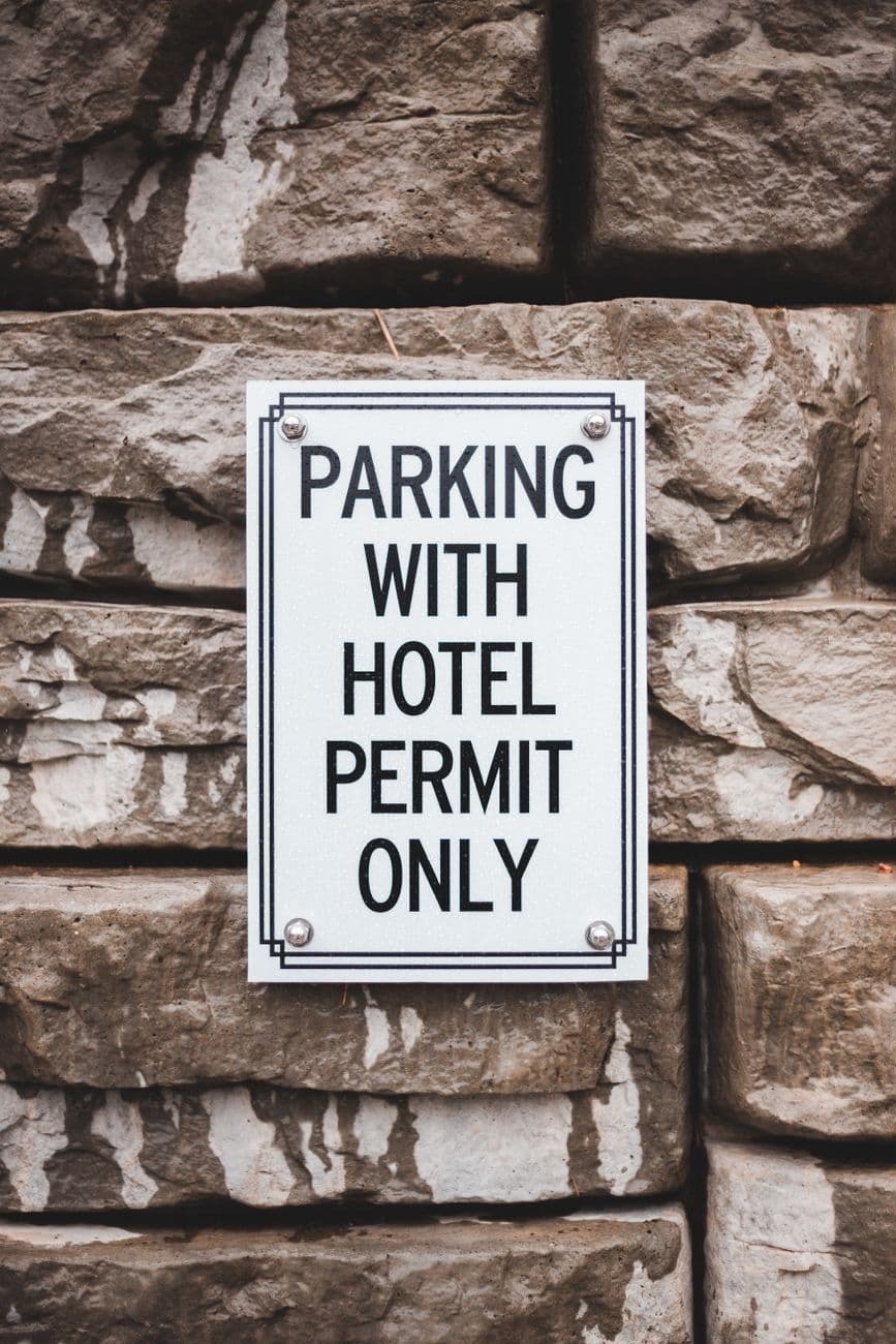 Rectangular shaped signboard with title about parking on shabby masonry hotel building wall in daylight