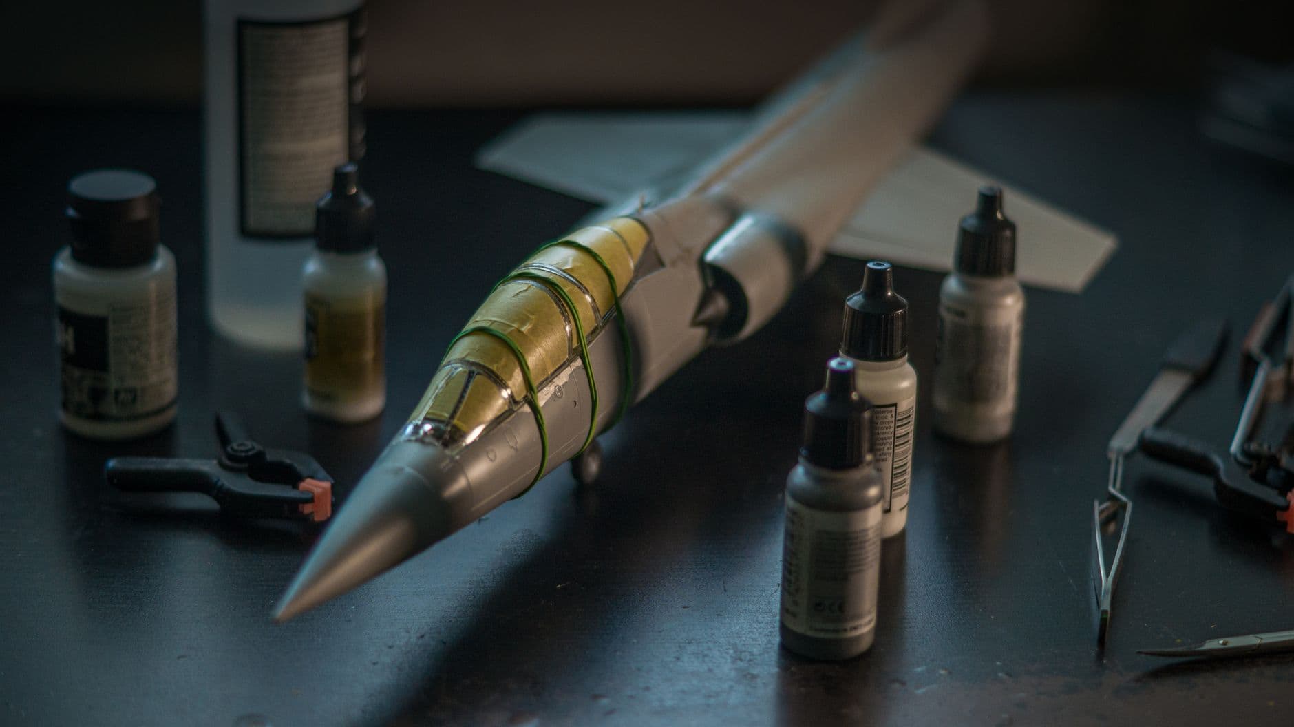 Close-up of a scale model F-104 Starfighter with modeling tools and paints on a desk.