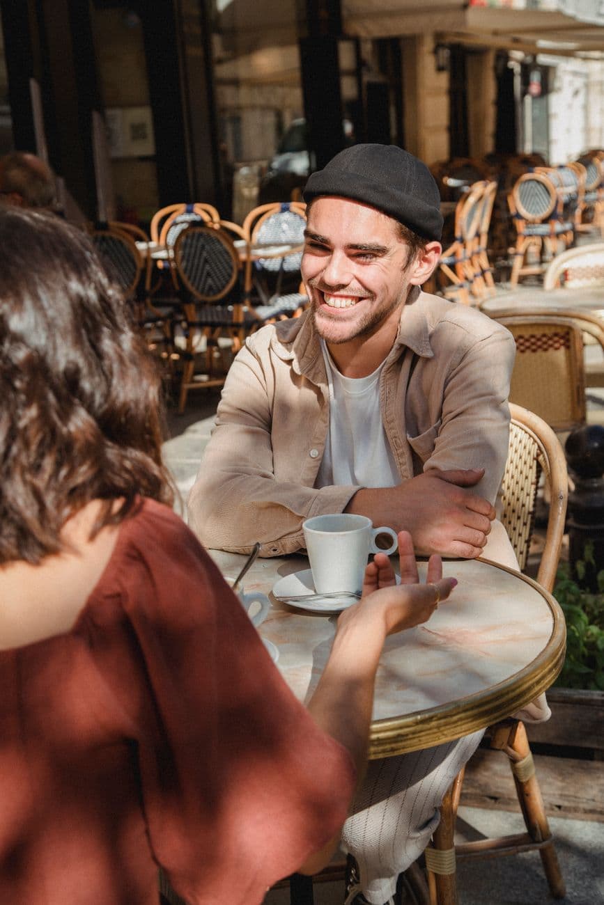 Two friends enjoying a casual coffee at an outdoor café on a sunny day.