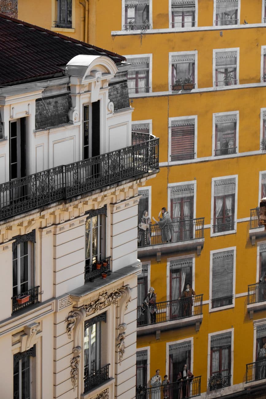 Elegant French architecture featuring trompe-l'oeil windows on a vibrant building facade.