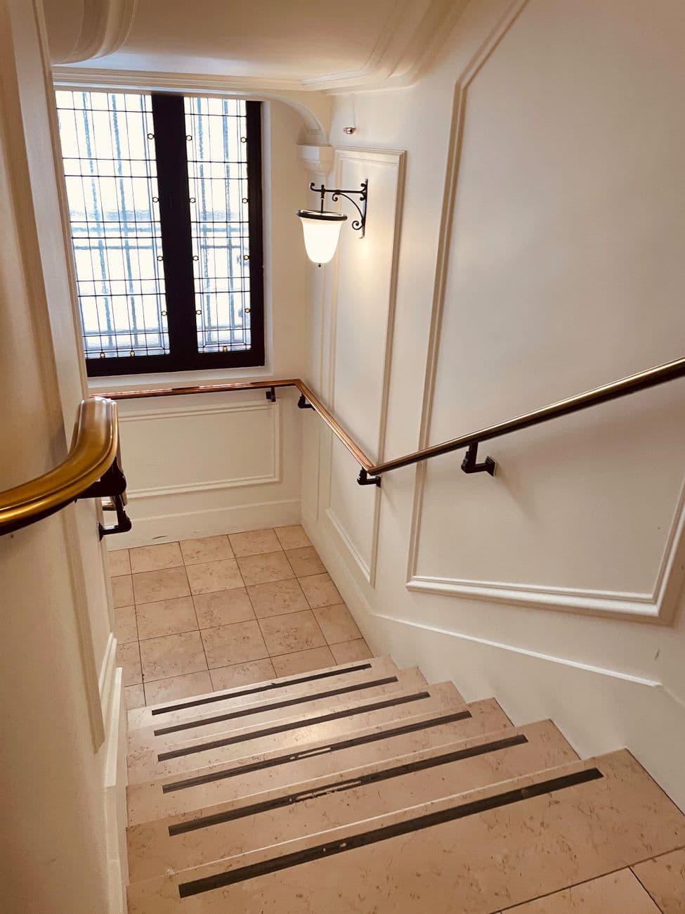 Capture of a classic stairwell in Paris with elegant details and warm lighting. Ideal for interior design themes.