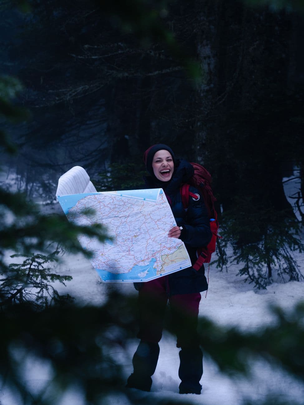 Traveler with map exploring snowy forest during winter hike. Adventure and navigation concept.