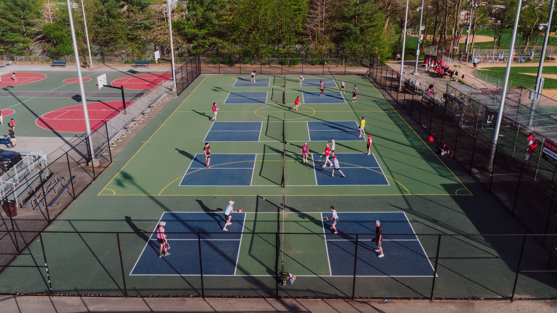 A lively pickleball game at outdoor courts in Philadelphia, captured from above on a sunny day.