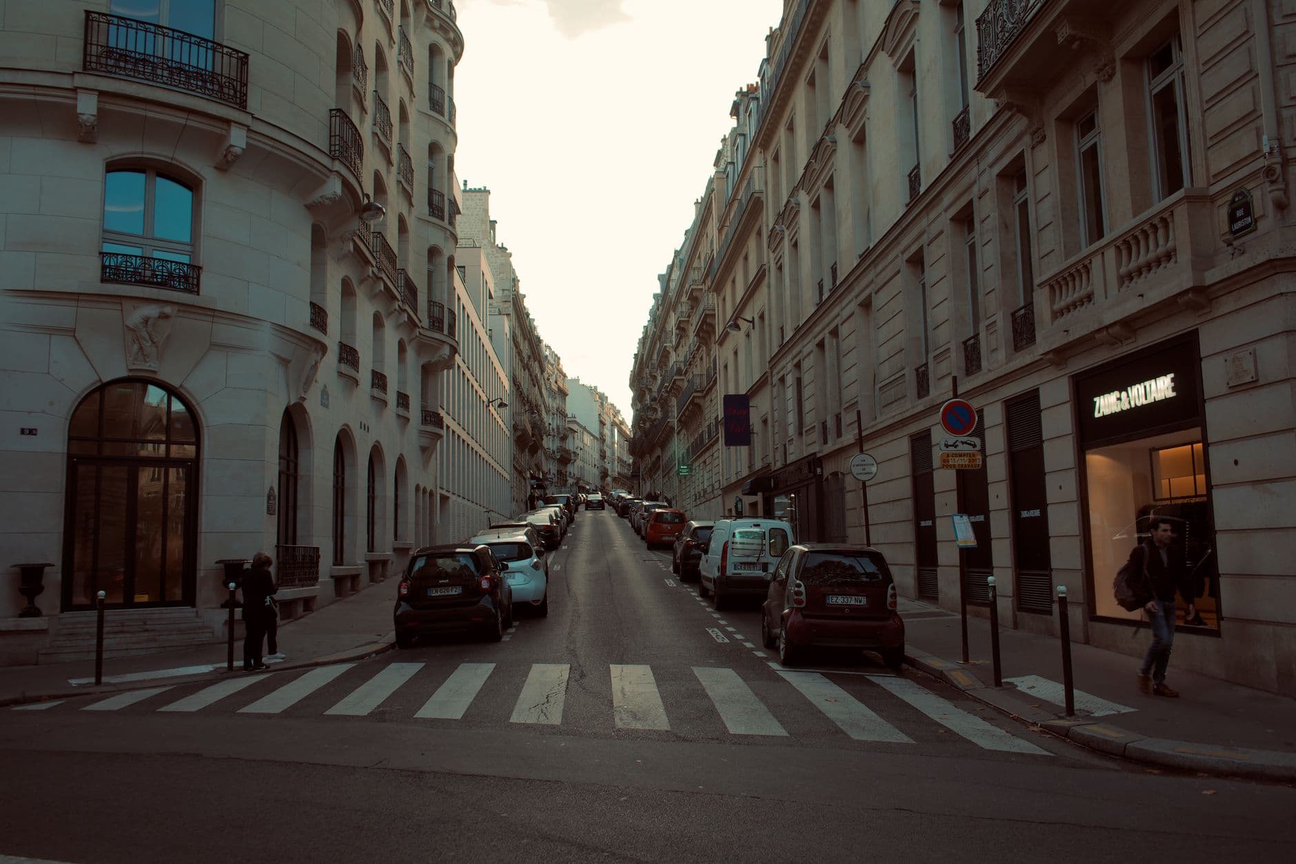 A picturesque European street lined with classic architecture and parked cars.