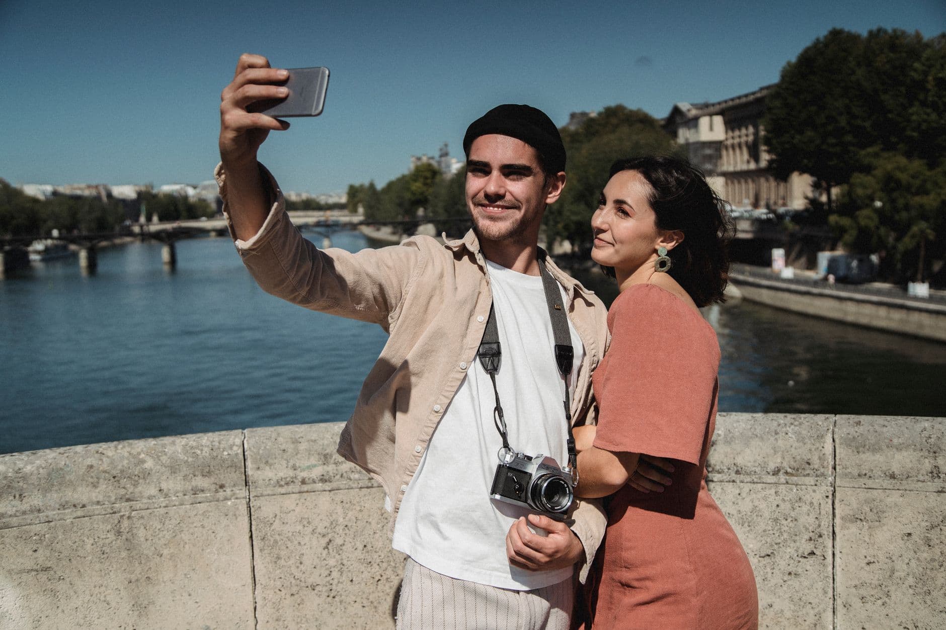 A young couple enjoys a romantic moment taking a selfie by a river. Perfect for lifestyle images.