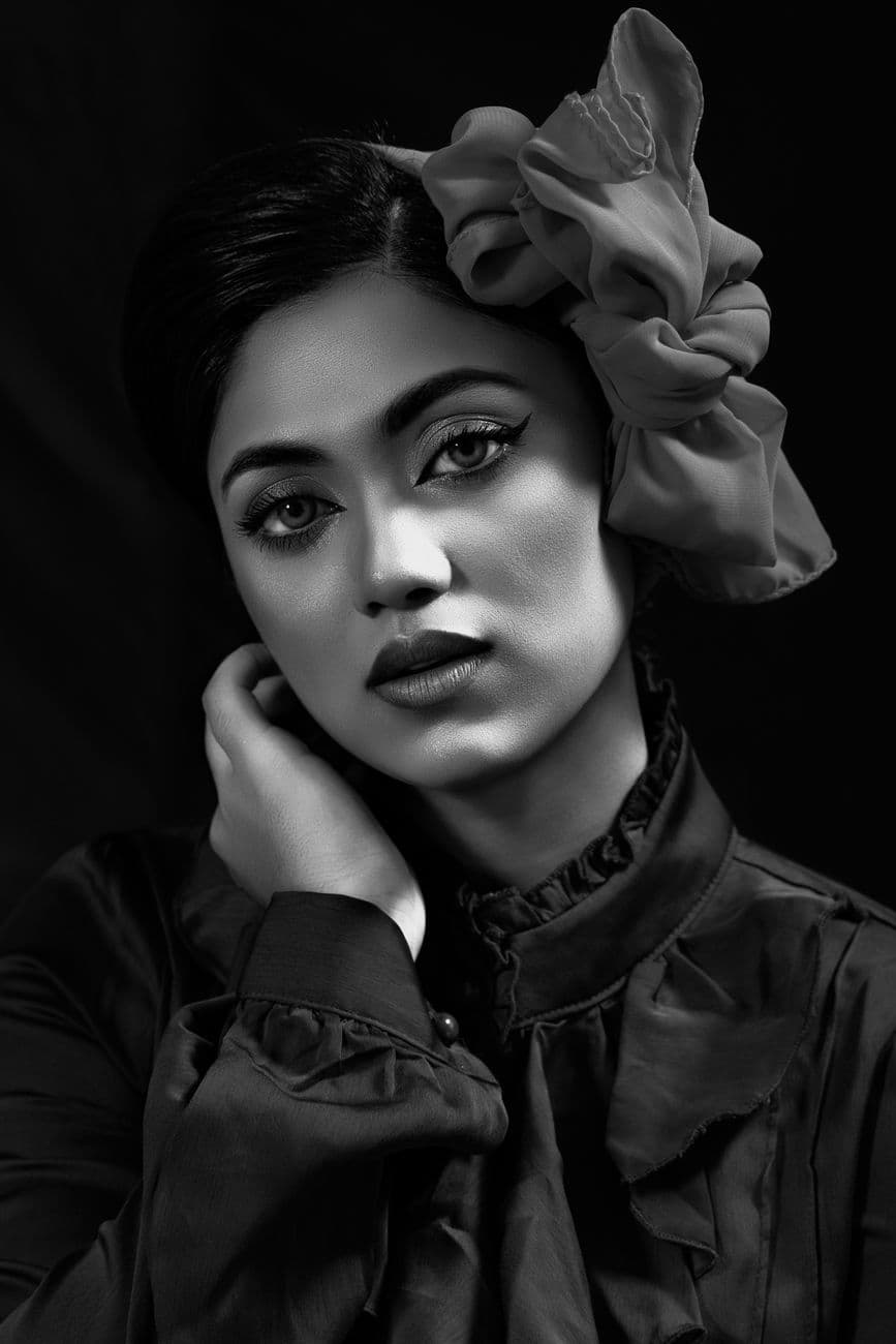 A striking black and white portrait of a woman with a flower accessory, showcasing elegance and style.