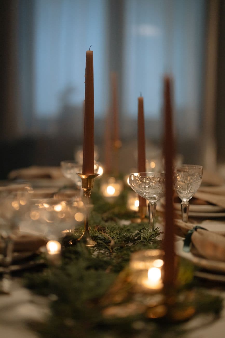 Cozy festive dining table with candles and greenery, perfect for holiday celebrations.