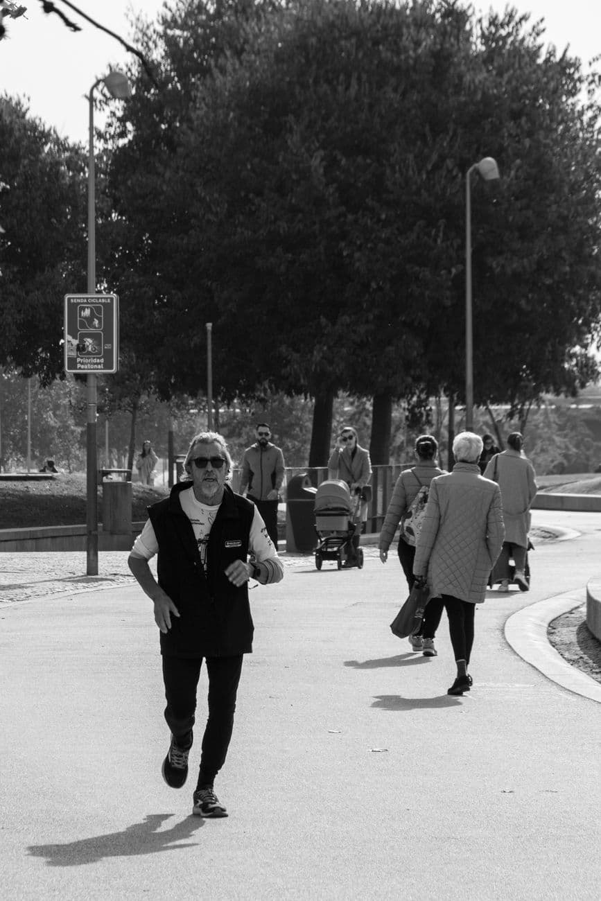 Black and white photo of people walking and jogging in a park in Madrid, capturing daily life.