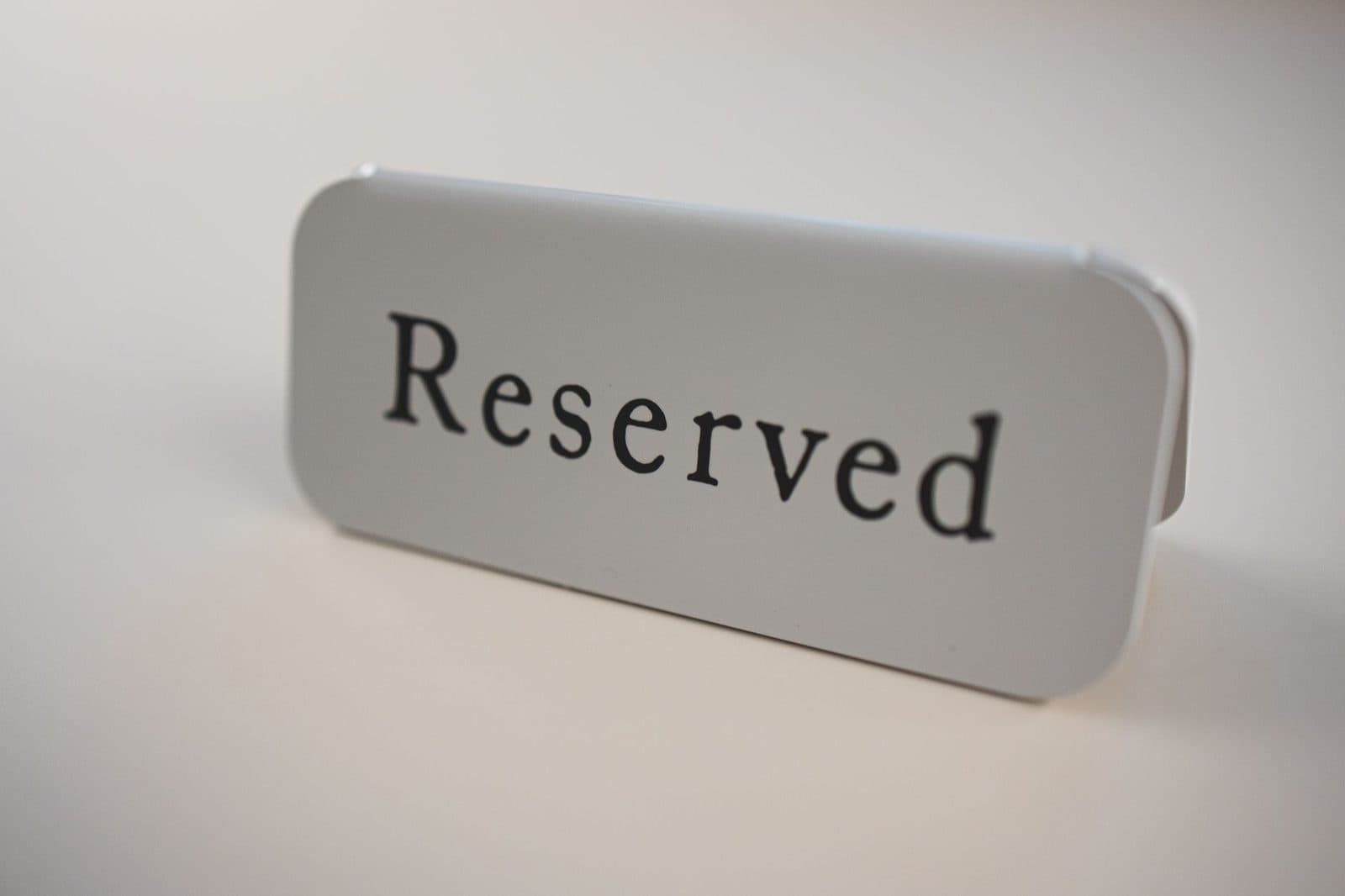 Small gray metal signage with black letters saying Reserved used on tables in cafes and restaurants