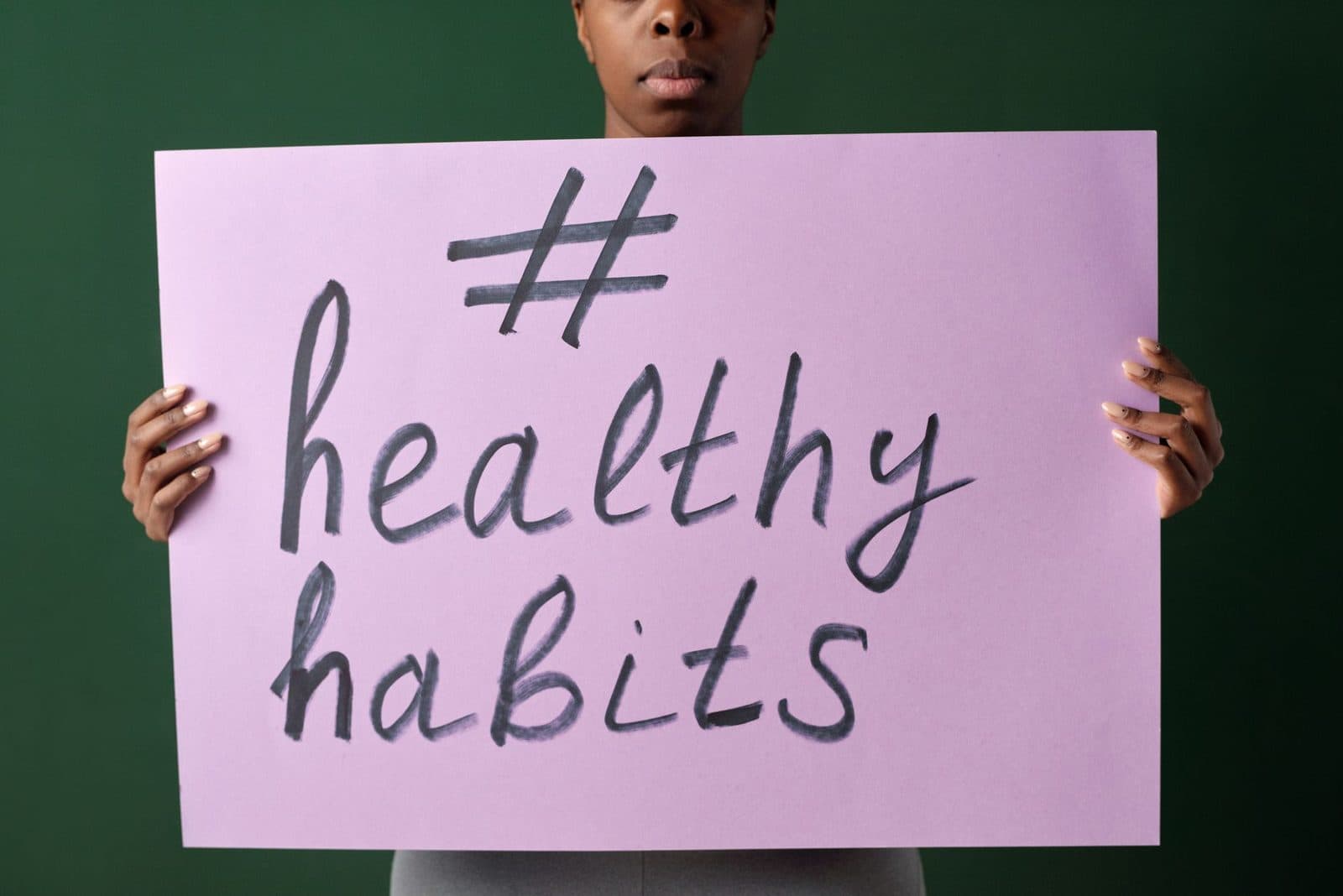 Person holding a "#healthyhabits" sign, emphasizing wellness.