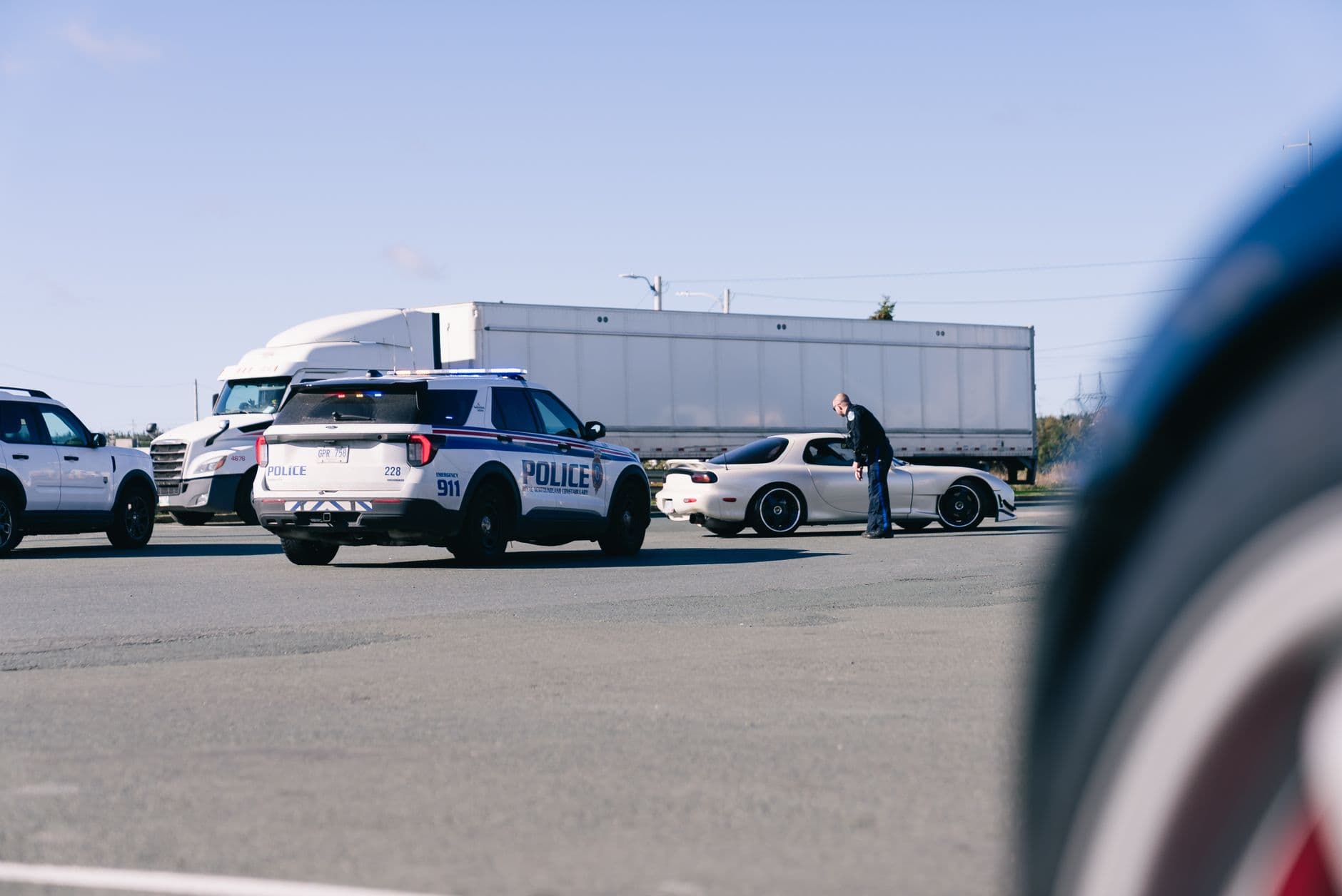 A police officer is interacting with a driver during a traffic stop on a sunny day.