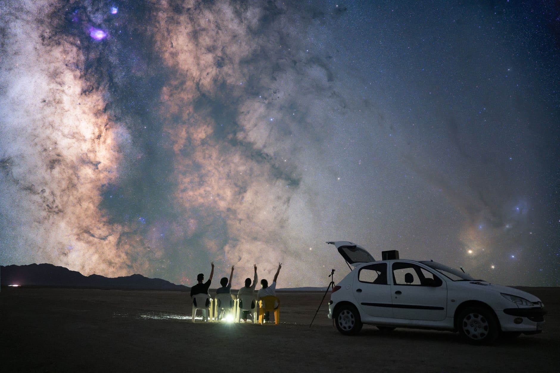 A group of stargazers observing the Milky Way in Semnan, Iran with a car and telescope.