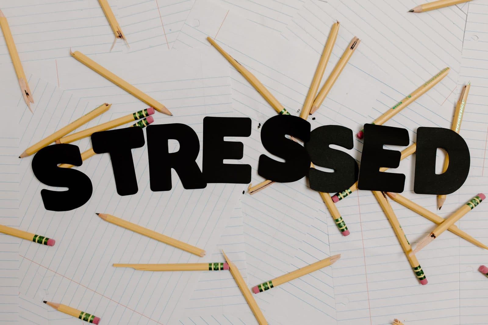 Stylized word 'stressed' with scattered pencils on paper, symbolizing anxiety and burnout.