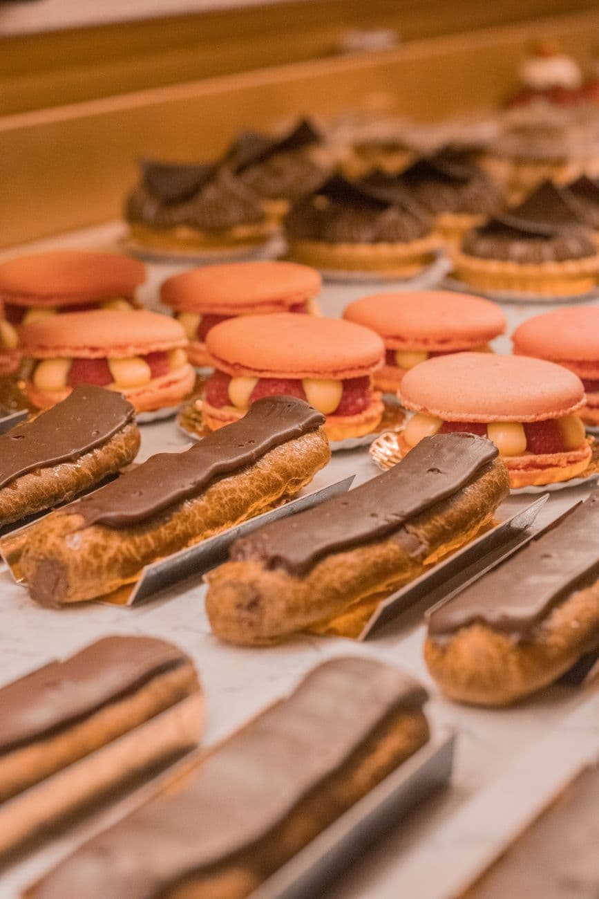 A close-up view of delectable pastries including eclairs and macarons in a bakery.