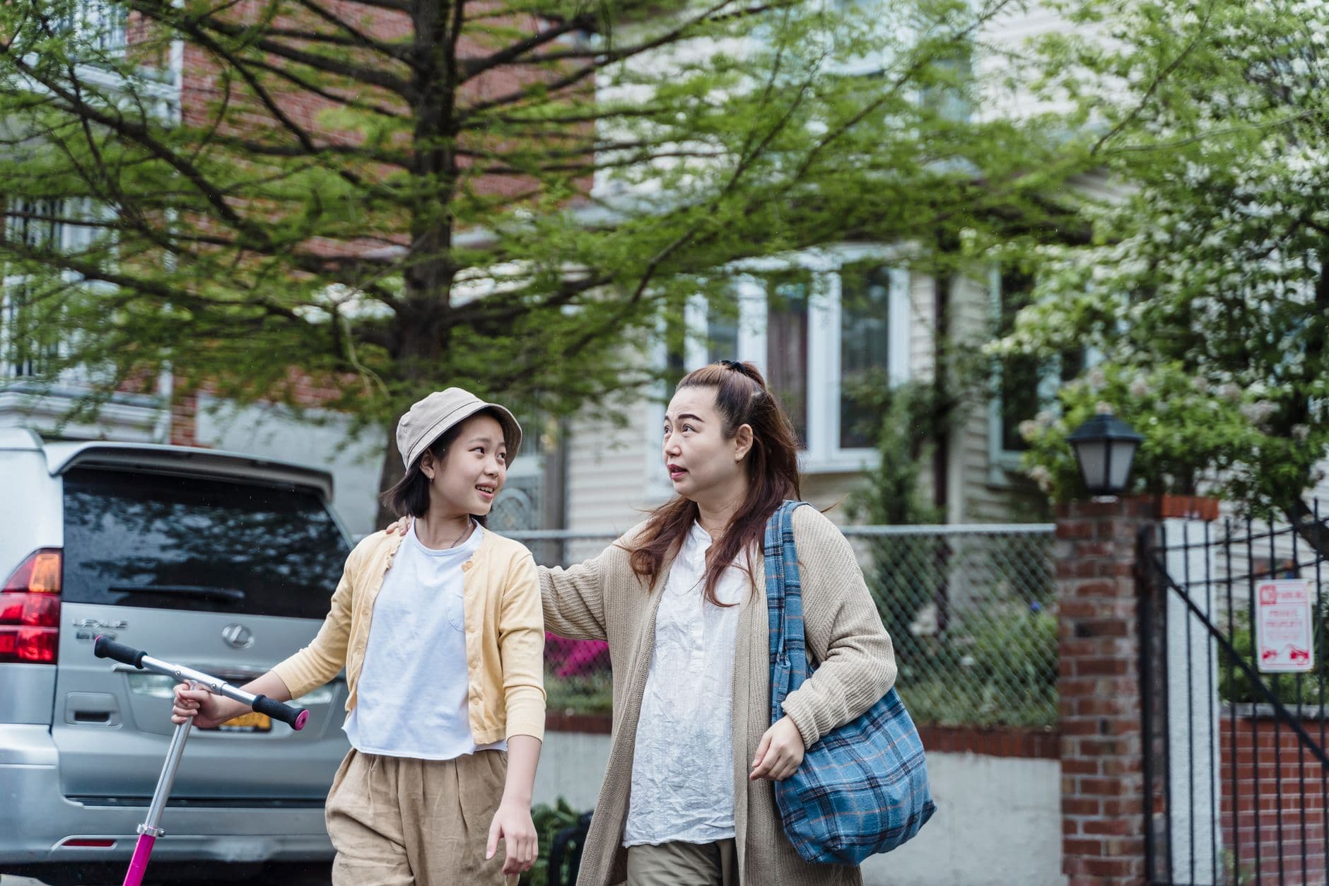 A mother and daughter walking together outdoors, enjoying a sunny day.